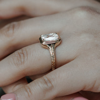 Old mine cut diamond on a bezel set and engraved engagement ring sits pretty on fingers under natural light.