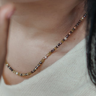 Raw diamond brown and yellow necklace with yellow gold beads sitting on neck of woman.