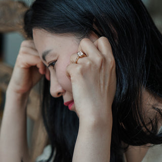 Woman thinking about something while wearing a cushion cut bezel engagement ring.