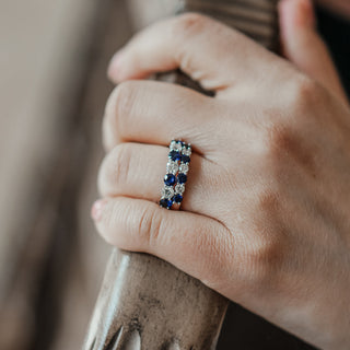 Two natural blue sapphires and natural diamond wedding bands sitting next to each other on a hand.