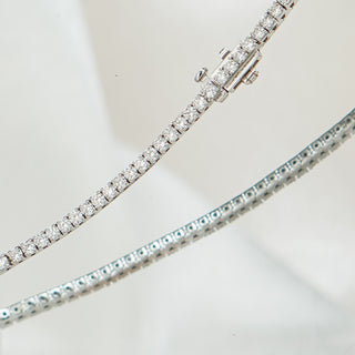 White gold lab grown diamond tennis bracelet close view, two strands crossing with box clasp and round brilliant stones in frame.