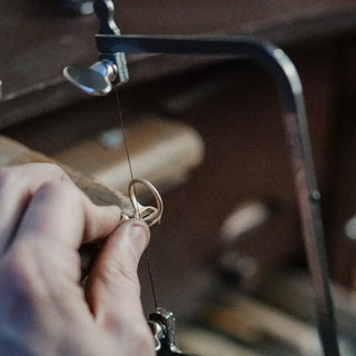 Bench jeweler cutting a seat and setting a stone in an engagement ring at the Vancouver studio.