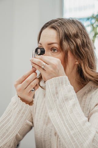 Jeweler examining a Diamond through a loupe while assessing ethical sourcing at the Atelier Fine Co. studio in Vancouver.