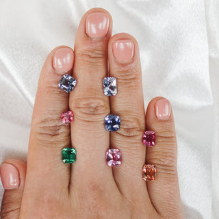 Loose colored gemstones held in the hand showing a range of colors.