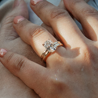 Oval engagement ring worn on the hand in sunlight.