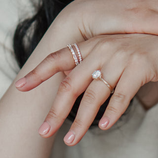Round brilliant diamond ring with diamond bands on pointer finger.