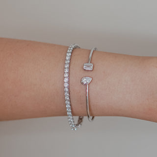Lab diamond toi et moi bangle worn stacked with a white gold tennis bracelet, bezel set stones meeting at the wrist.