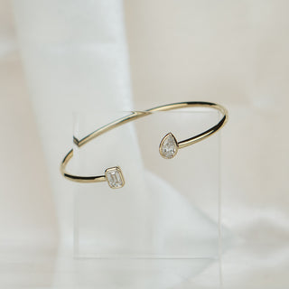 Toi et moi lab diamond bangle in yellow gold standing upright, open cuff profile against soft white fabric.