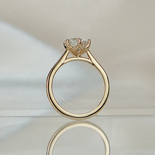 Round brilliant lab diamond flower head ring standing upright with reflection, petal-like prongs above the cathedral arch.