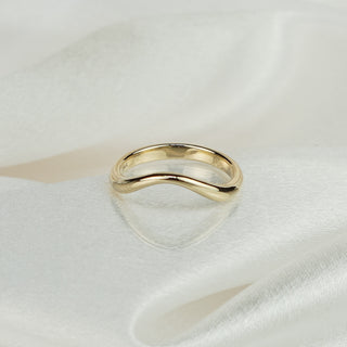 14k yellow gold shadow wedding band on white satin fabric, gentle curve with tapered middle visible.
