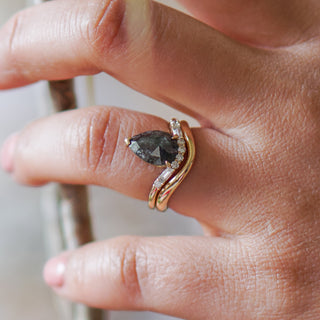 Shadow wedding band in yellow gold worn with a dark pear shape engagement ring, tapered curve following the stone.