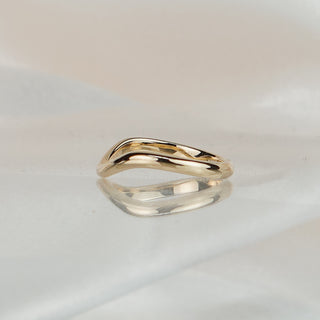 Curved yellow gold shadow band nested against a second band on soft fabric, flush fit at the taper.