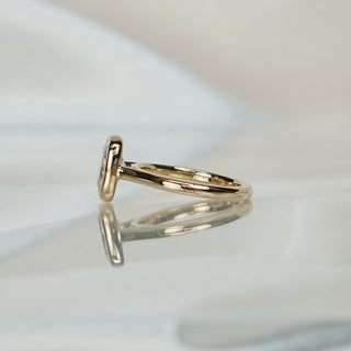 Side view of a cushion bezel cathedral engagement ring, the bezel wall and shank arch meeting in yellow gold.