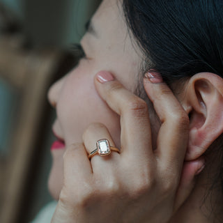 Woman wearing a cushion bezel diamond ring on a yellow gold setting.