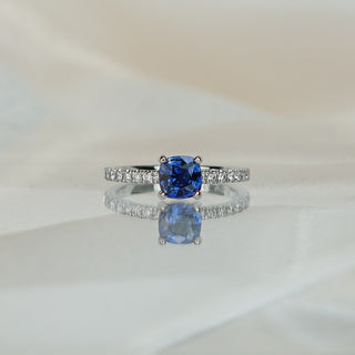 White gold engagement ring with a 1.00 carat cushion cut blue Sapphire and pavé Diamond shank.