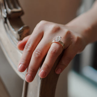Lab grown diamond double shank engagement ring worn on the hand, cushion center in a four-prong setting.