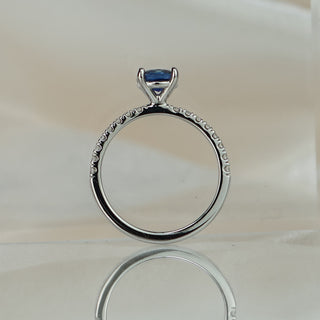 Cushion cut blue Sapphire engagement ring standing upright with reflection, showing the gallery beneath the center stone.