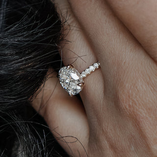 Oval hidden halo engagement ring worn on the hand, concealed round brilliants beneath the center in yellow gold.