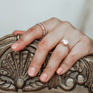 Hand wearing a ring on a decorative wooden surface