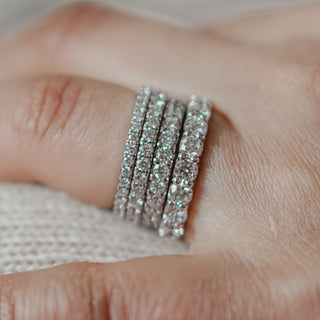 Diamond pave wedding rings in four sizes on finger.