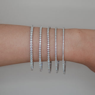 White gold diamond tennis bracelet in five sizes on wrist.