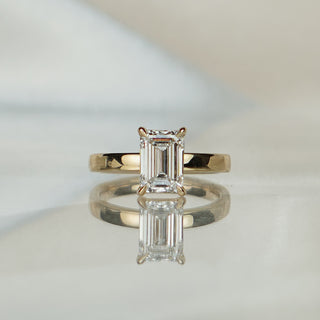 Yellow gold solitaire with a 2.08 carat emerald cut lab diamond, uniform 2.75mm pipe shank circling the finger.
