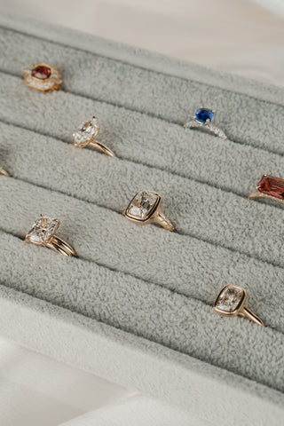 Collection of diamond and sapphire engagement rings on a gray tray.