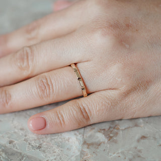 Faceted yellow gold wedding band worn on the hand, flat panels catching light along the slim 2.3mm band.