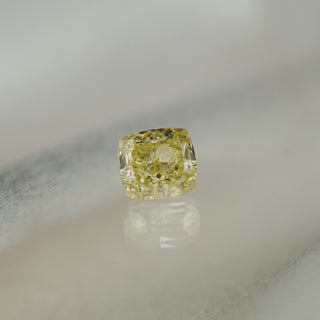 Yellow diamond on a reflective surface with a neutral background