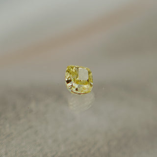 Yellow diamond on a reflective surface with a blurred background