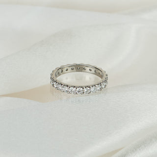 Lab grown diamond full eternity band in white gold on satin fabric, twenty-four round brilliants in scallop shared prongs around the full circumference.