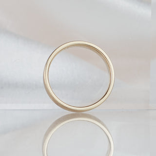 Flat profile yellow gold wedding band standing upright against a soft neutral backdrop, squared edges and 4.1mm width visible.