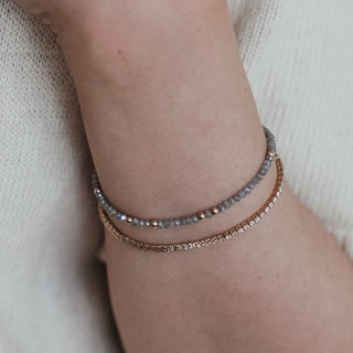 Grey raw faceted Diamond bracelet worn on the wrist with gold bead accents, styled against a cream sweater.
