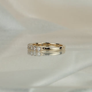 Half eternity lab diamond wedding band standing upright with reflection, shared claws holding the round brilliants.
