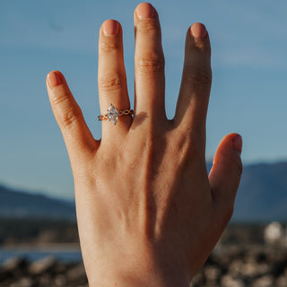 Hand wearing marquise braided shank engagement ring at a Vancouver beach.