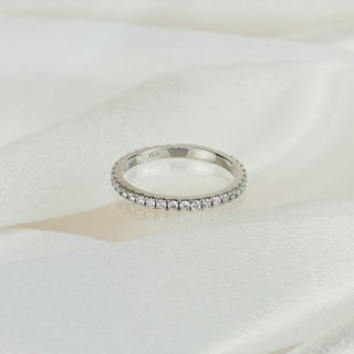Lab grown diamond micro pavé wedding band in white gold on satin fabric, thirty-three small round brilliants wrapping the band.