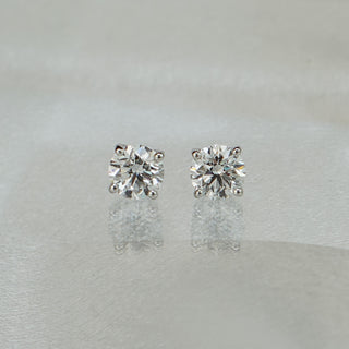 Pair of round brilliant lab grown diamond studs facing forward, matched stones on a soft neutral background.