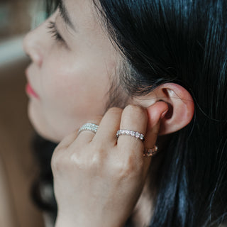 White gold scallop shared claw band worn on the hand, round lab diamonds visible as the hand rests near the ear.