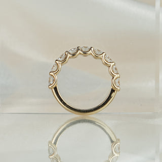 Scallop half eternity band standing upright with reflection, U-shaped seats visible beneath nine round brilliants.