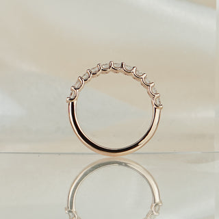 Shared prong lab diamond band standing upright with reflection, showing open claws and the plain polished back half.
