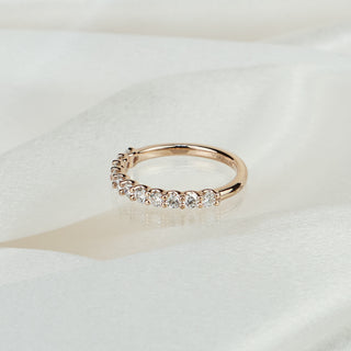 Lab grown diamond shared prong wedding band in rose gold on satin fabric, round brilliants across the front of the band.