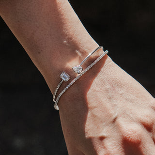 Two white gold lab diamond tennis bracelets worn together in natural light, stones catching sun on the wrist.