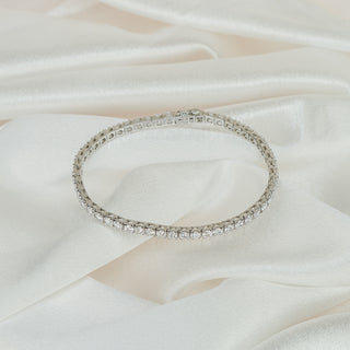 Full circle view of a white gold lab grown diamond tennis bracelet clasped closed on ivory satin.
