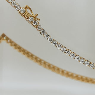 Yellow gold lab grown diamond tennis bracelet close view, round brilliant stones in a continuous line with box clasp and safety catch visible.