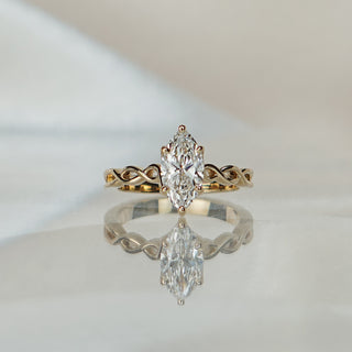 Yellow gold solitaire with a 1.22 carat marquise cut lab grown diamond over a braided shank, upright silhouette in frame.