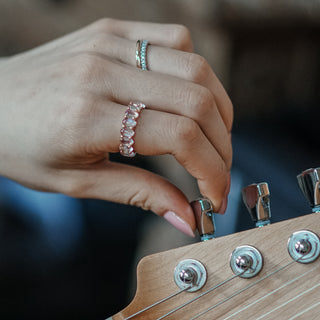 Natural Moonstone eternity ring worn on the hand while adjusting a guitar, milky oval stones over rose gold.
