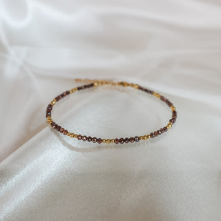 Natural brown raw faceted Diamond bracelet on white satin fabric, 50 brown diamonds with yellow gold beads clasped in a circle.