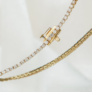 Close view of the box clasp and safety catch on a yellow gold natural Diamond tennis bracelet, round brilliant stones on either side.