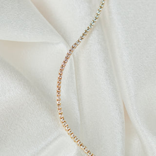 Natural Diamond tennis bracelet in yellow gold draped on ivory satin, prong set stones catching light along the strand.