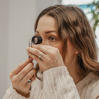 Nina examining a Diamond through a jeweler's loupe in profile at the studio.